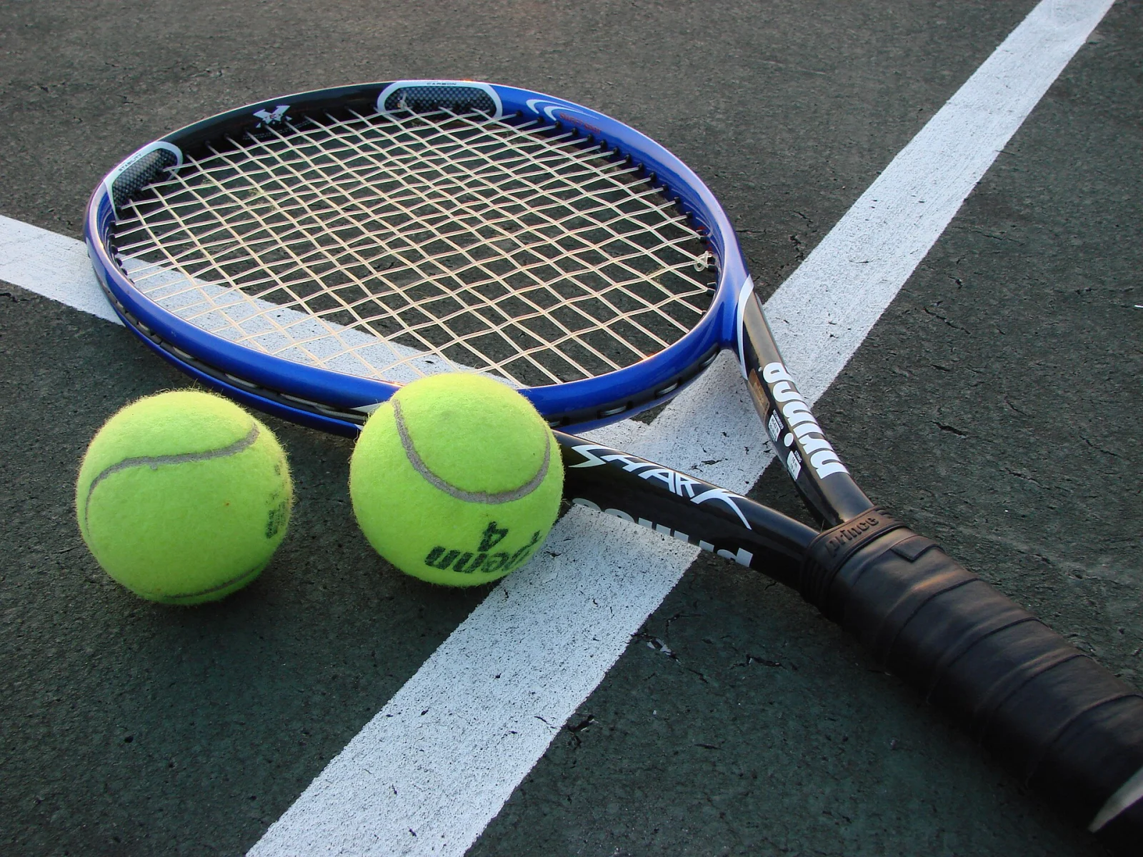 Tennisracket och två tennisbollar på en tennisbana