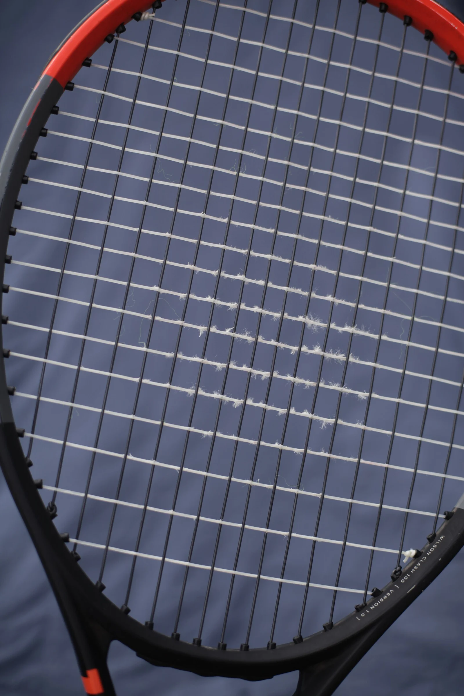 Tennisracket med tydligt sliten och fransad tvärsträng